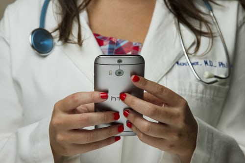 female doctor in lab coat on smartphone